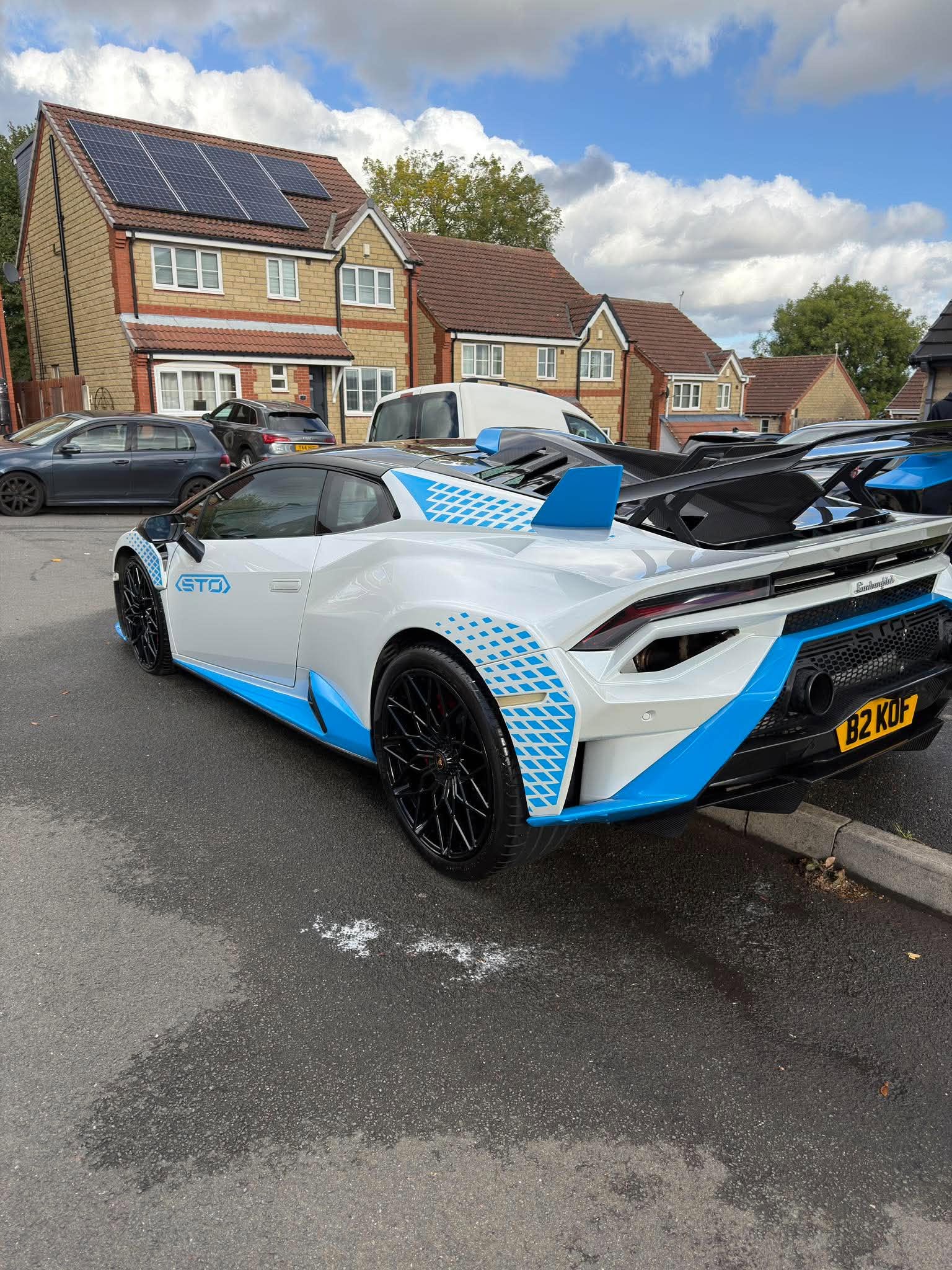 Rear three-quarter view of a white and blue Lamborghini Huracán STO after exterior detailing